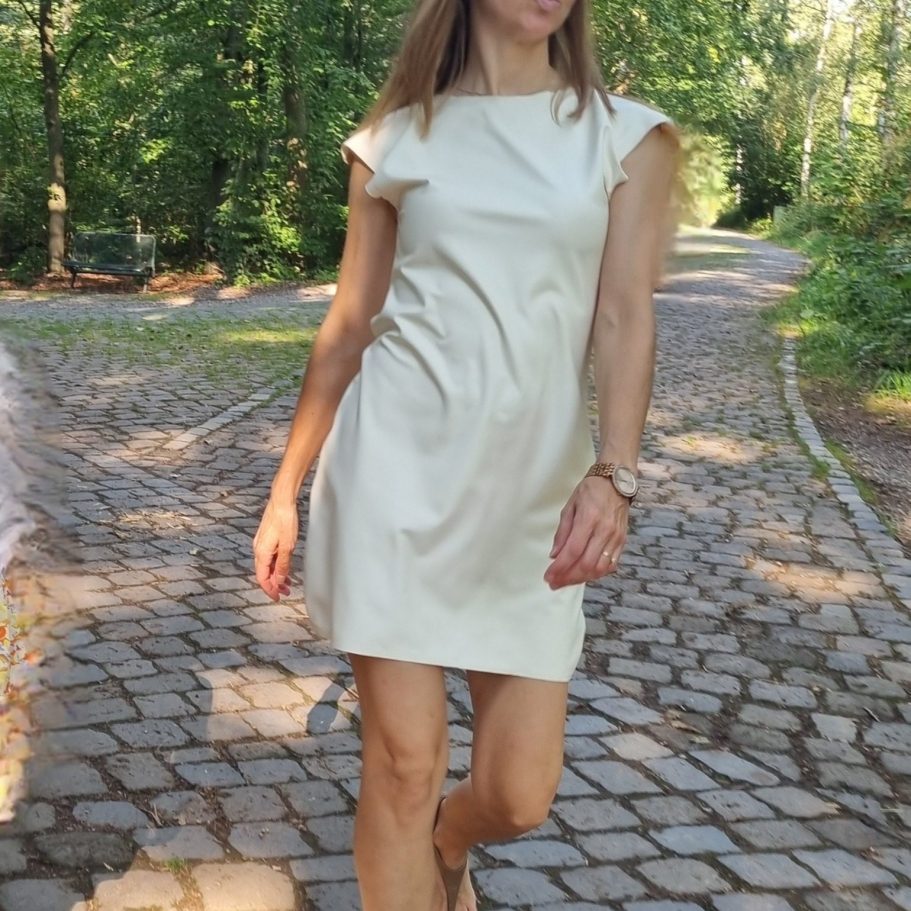 Latexkleid Latexkleid cremefarben, kombiniert mit goldener Uhr und schwarzen Sandalen.