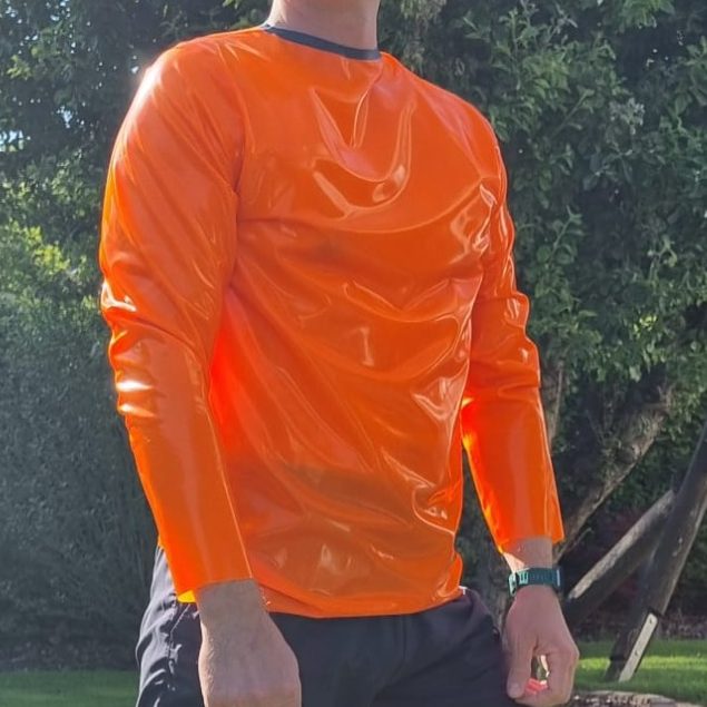 Latexshirt langarm Langärmliges Latexshirt in neonorange mit Kontrastnaht in blau, getragen in schönem Garten.